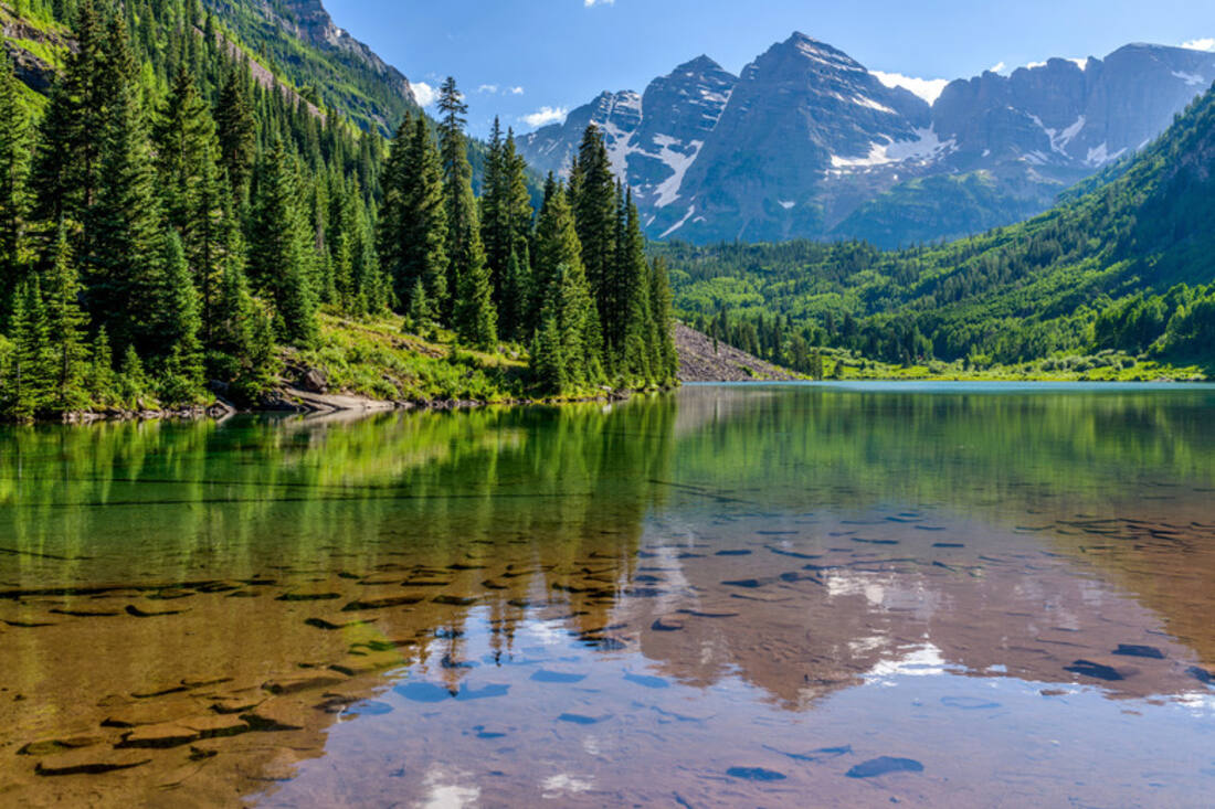 A calm mountain lake reflecting a forested valley